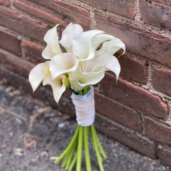 Small bouquet of white calla lilies tied with white ribbon