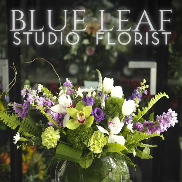Purple and white floral arrangement in a round glass vase