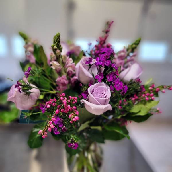 Lavender roses and purple filler flowers in a glass vase