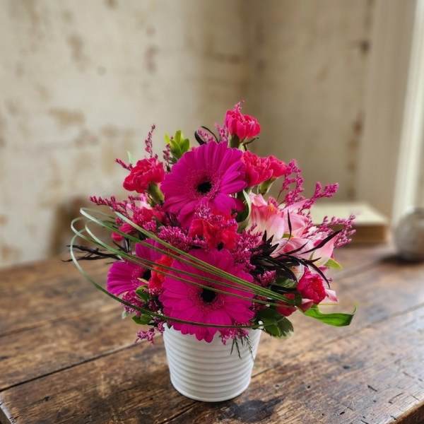 Bright pink mixed bouquet in a white ribbed pot
