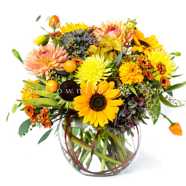 Mixed bouquet of sunflowers, dahlias, and chrysanthemums in a clear glass vase