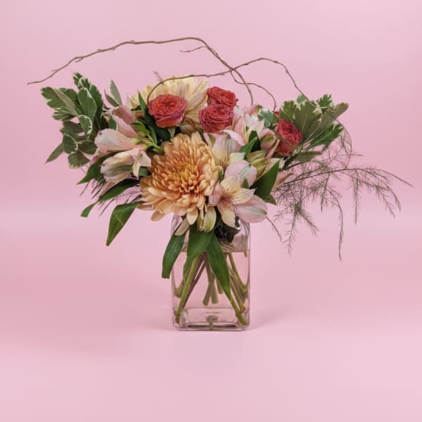 Mixed pink and peach flowers in a clear glass vase