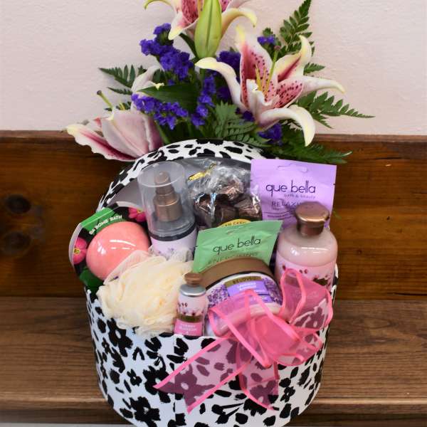 Gift basket with lilies and bath products in a black-and-white patterned box