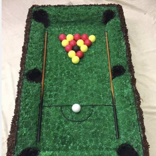 Miniature pool table made of green material with colored balls and cues