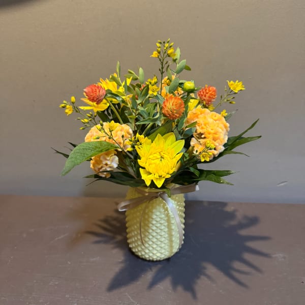 Yellow and orange floral arrangement in a textured vase with a ribbon