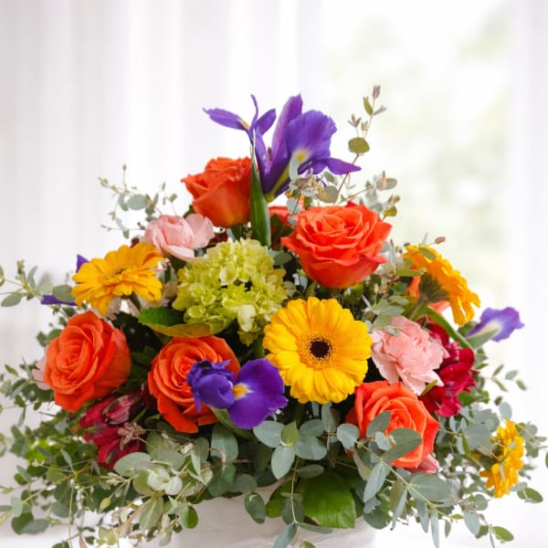 Colorful mixed bouquet in a white vase with a sheer ribbon