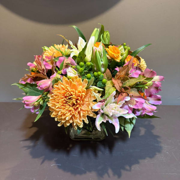 Mixed bouquet of orange, pink, and white flowers in a glass vase