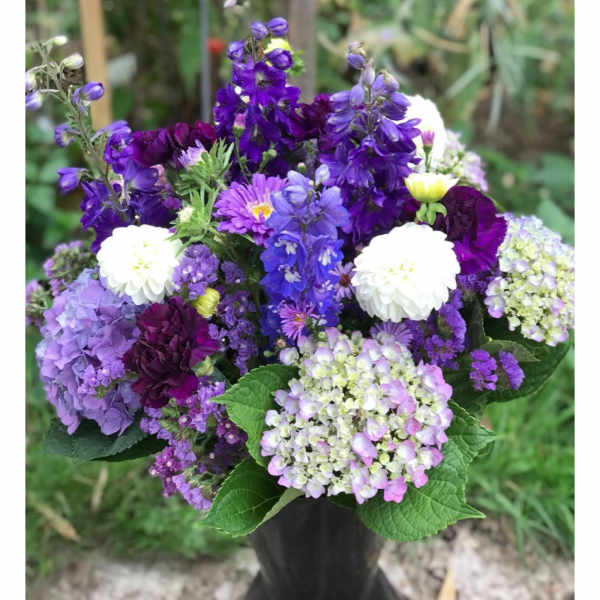 Purple and white mixed flower bouquet in a dark vase