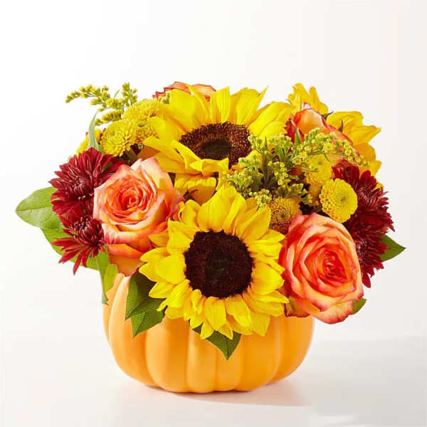 Sunflowers, roses, and mums arranged in a pumpkin-shaped container