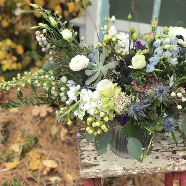 Mixed bouquet in a metal container with white, blue, and green flowers
