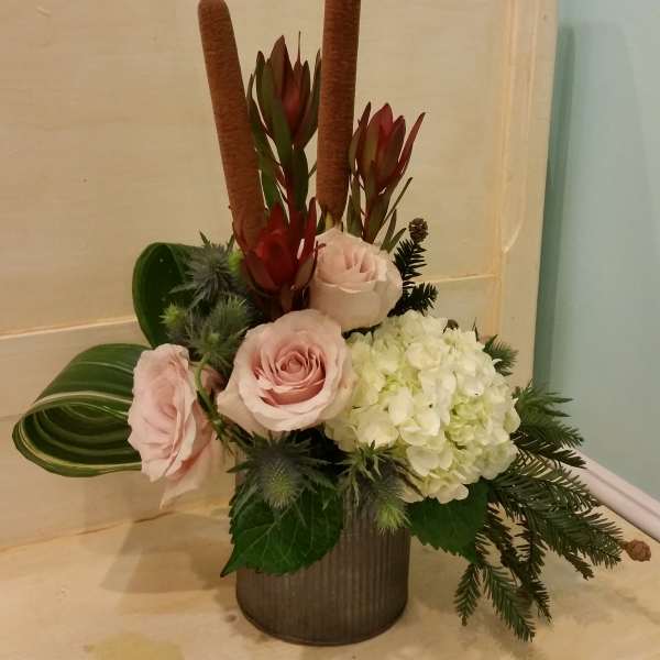 Pink roses and white hydrangea in a vase with tall brown cattails