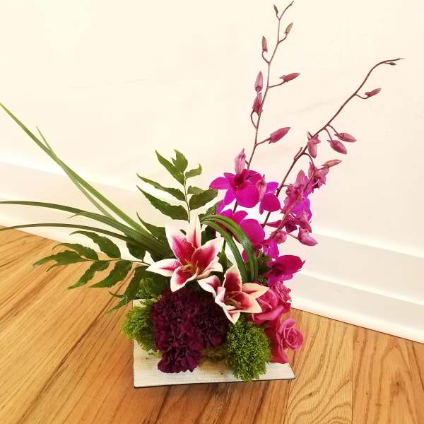 Pink orchid and lily arrangement in a low square container
