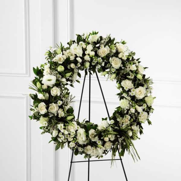 Large white rose and daisy wreath displayed on a black metal easel
