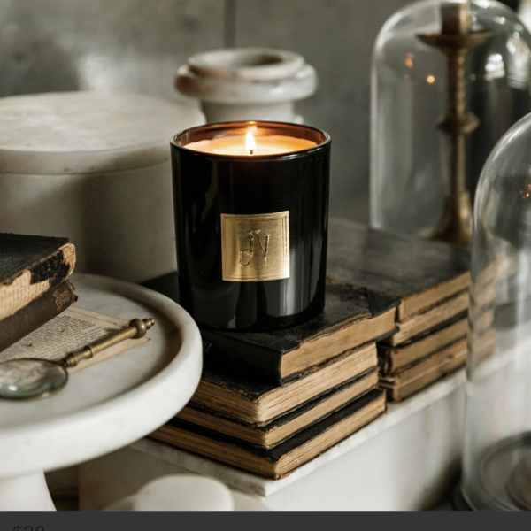 Lit black candle in a glass jar on stacked books