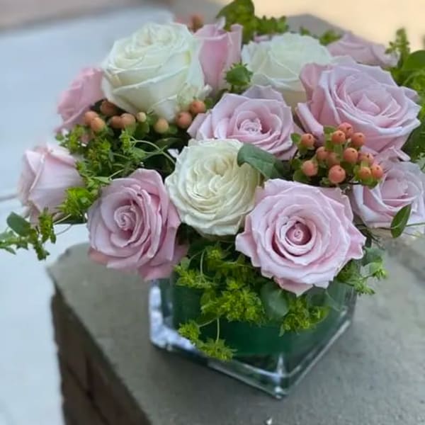Pink and white roses arranged in a square glass vase