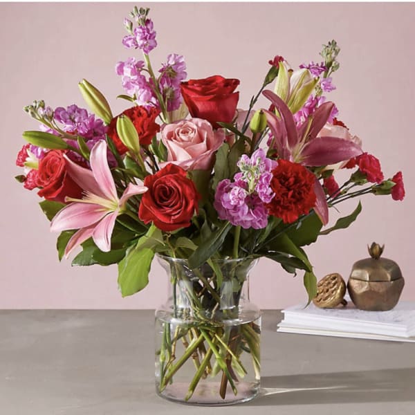 Mixed bouquet of red and pink flowers in a clear glass vase