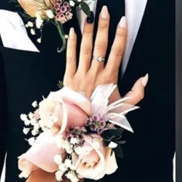 Two floral wrist corsages with pale pink roses and white accents