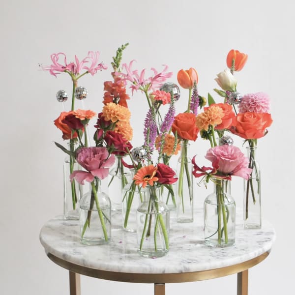 Small floral stems in clear glass bottles on a round table