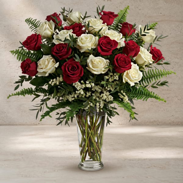Red and white roses arranged in a clear glass vase.