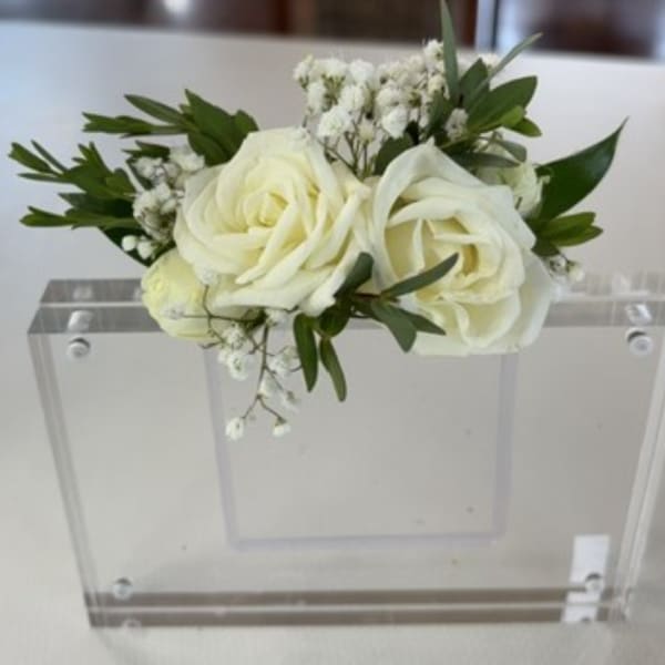 White rose bouquet with baby's breath and greenery on a clear acrylic chair