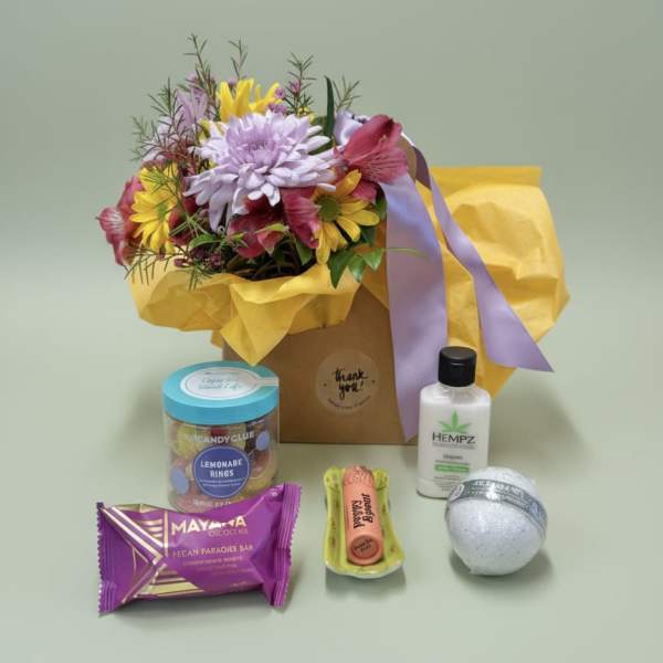 Mixed flower bouquet in a gift bag with assorted treats and a lotion bottle
