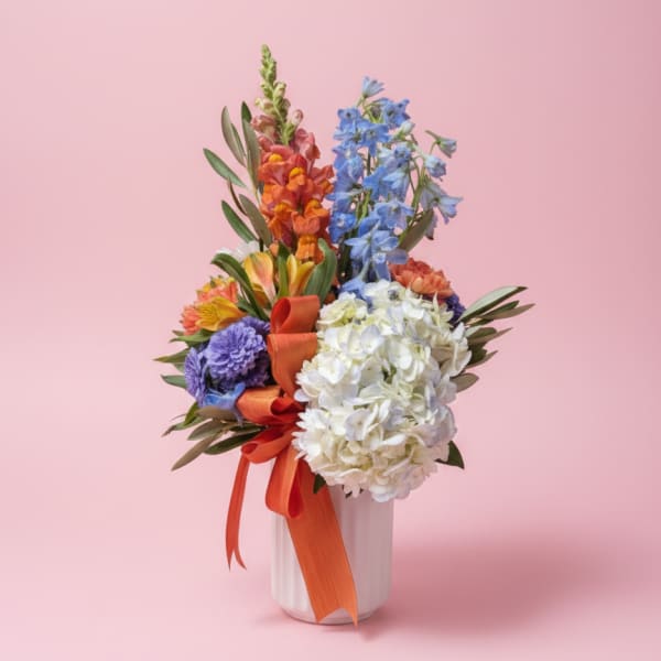 Colorful mixed bouquet in a white vase with orange ribbon