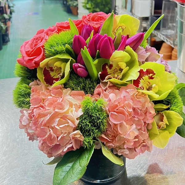 Bouquet of pink hydrangeas, roses, and lime orchids in a black vase