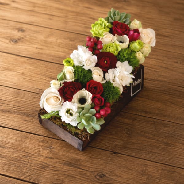 Rectangular floral arrangement with red, white, and green blooms in a wooden box