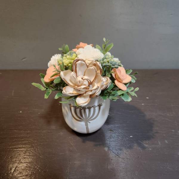 Small floral arrangement in a white ceramic pot with peach and cream blooms