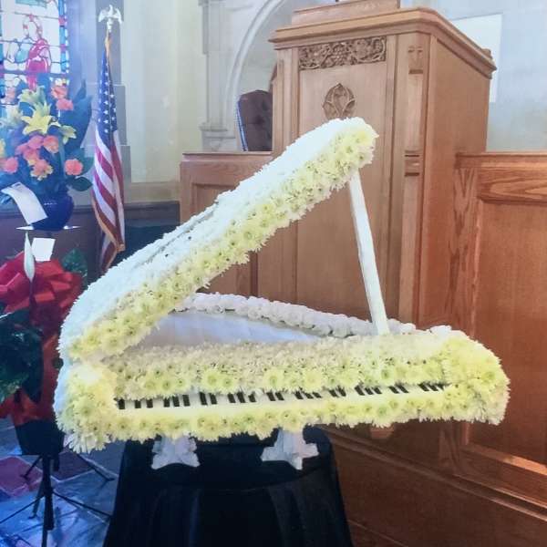White floral grand piano arrangement on a black draped stand