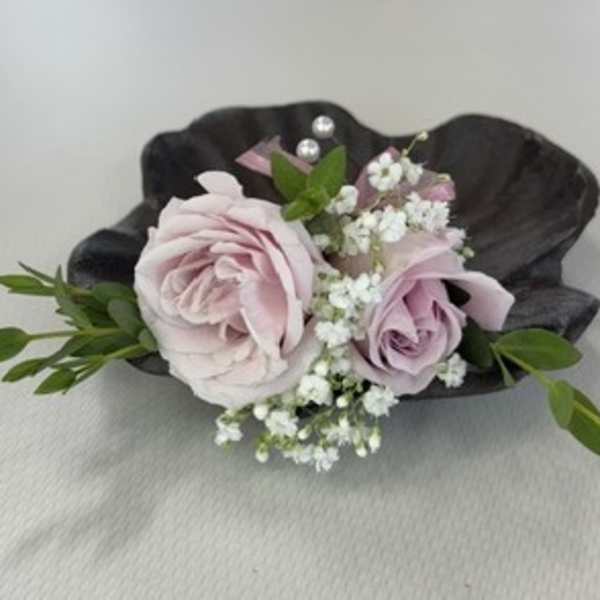 Small boutonniere with pale pink roses and white baby's breath on a dark shell
