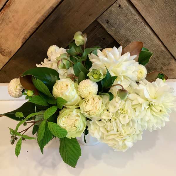White floral arrangement with roses, hydrangea, and dahlias in a white container