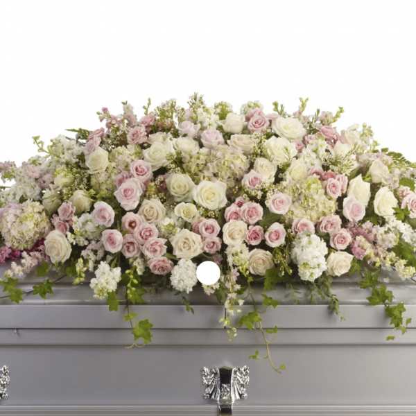 Pastel pink and white floral casket spray on a silver casket