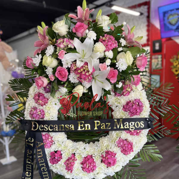 Large pink and white funeral wreath with lilies and roses on a stand