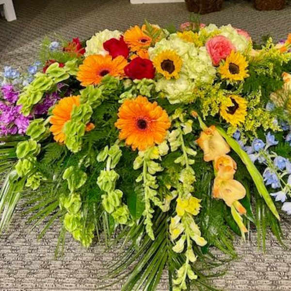 Large colorful floral spray with gerbera daisies, roses, and orchids