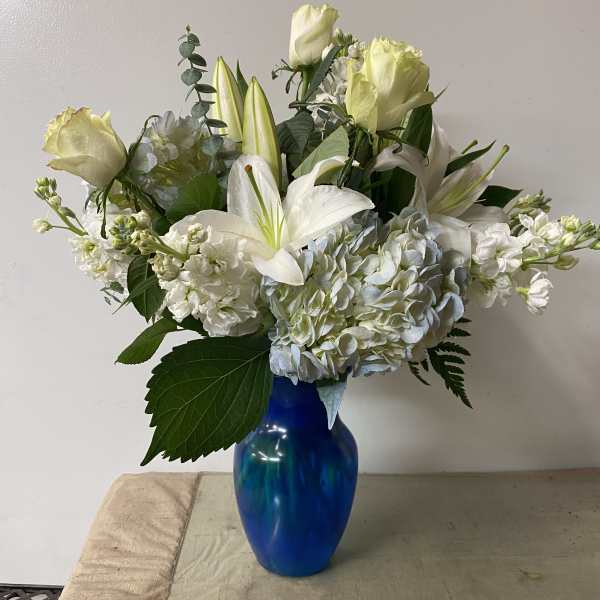 White roses and lilies arranged in a blue vase