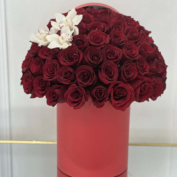 Red rose arrangement in a pink cylindrical box with white orchids
