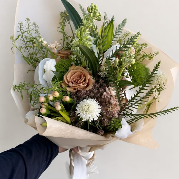 Hand-tied bouquet with tan, white, and pale pink flowers