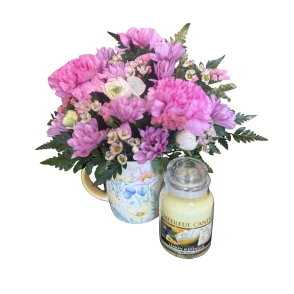 Pink mixed bouquet in a floral mug with a candle beside it