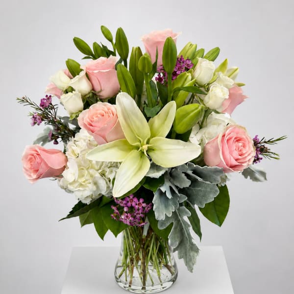 Pink roses and white lilies arranged in a clear glass vase