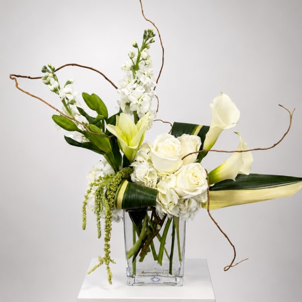 White roses, calla lilies, and orchids in a clear glass vase
