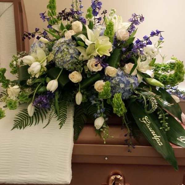 White and blue floral casket spray with purple accents
