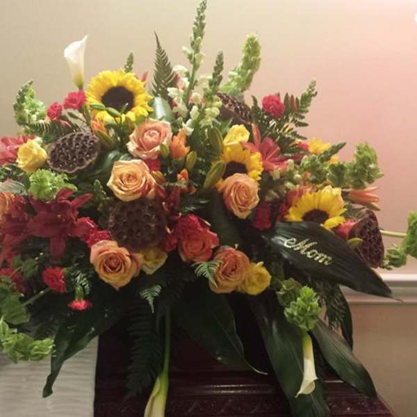Large mixed floral spray with sunflowers, roses, and lilies in warm colors