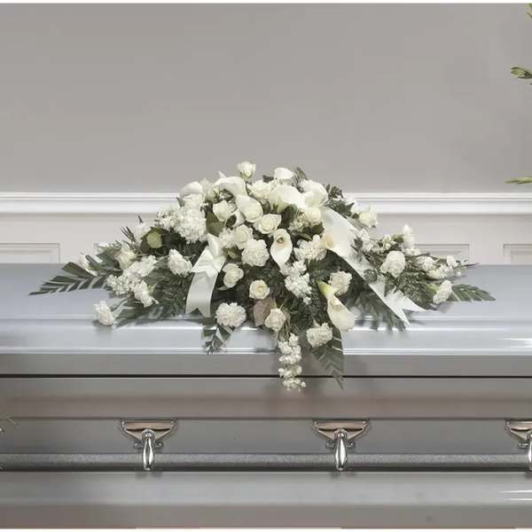 White floral casket spray with ribbons on a silver casket