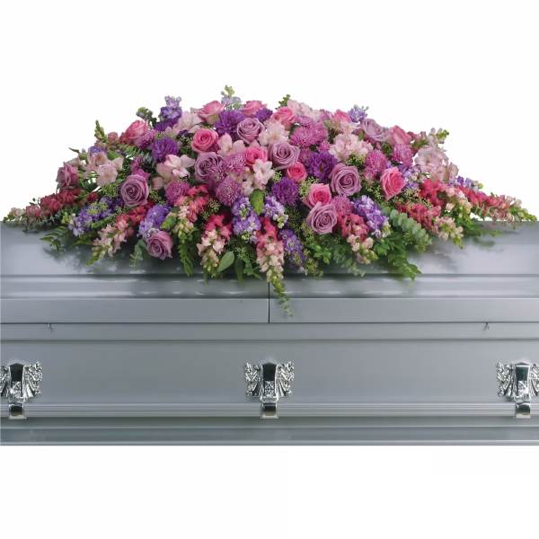 Large pink and purple floral casket spray on a silver casket