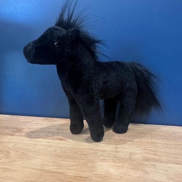 Black plush horse figurine on a wooden surface