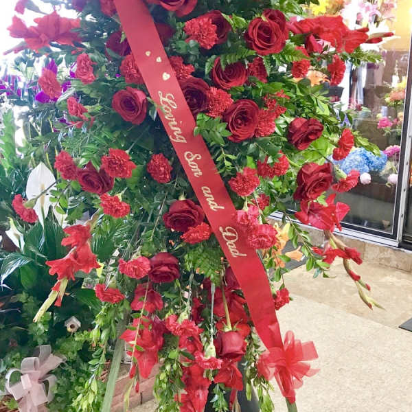 Large standing floral spray of red roses and carnations with a red ribbon
