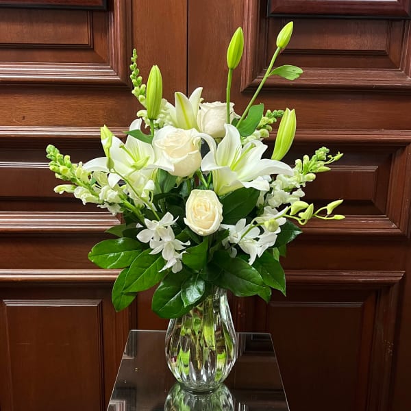 White lilies and roses in a clear glass vase