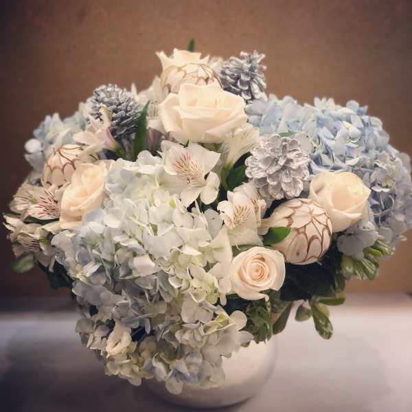 Bouquet of pale roses and blue hydrangeas in a white vase