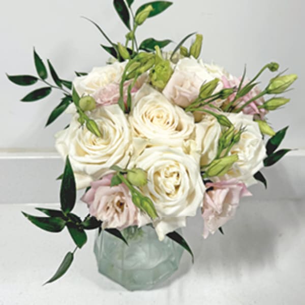 White and blush roses arranged in a glass vase